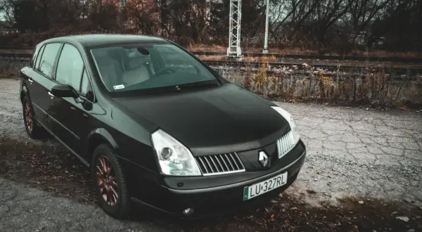 Czarny Renault Vel Satis z miedzianymi felgami stoi przy torach kolejowych.