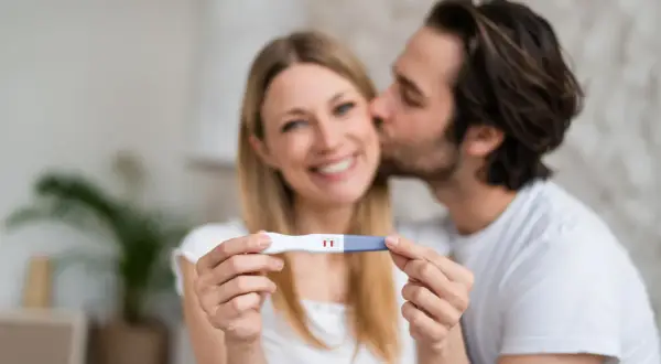 Szczęśliwa para trzyma test ciążowy z dwoma kreskami. Po trudnych doświadczeniach, to nowy początek i nadzieja na ciążę po poronieniu.