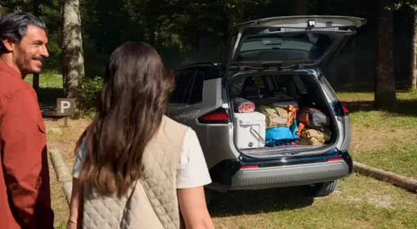 Para wycieczkowiczów podziwia bagażnik Toyoty RAV4, wypełniony po brzegi sprzętem. Imponująca pojemność bagażnika pomieści wszystko na weekendowy wypad.