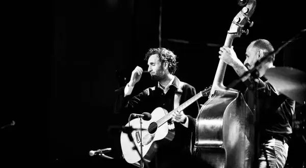 Julian Lage gra na gitarze akustycznej obok kontrabasisty na scenie.