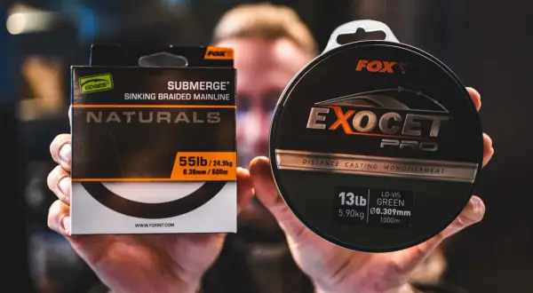 Wędkarz prezentuje żyłkę i plecionkę Fox. Wybór między żyłką a plecionką zależy od metody łowienia.