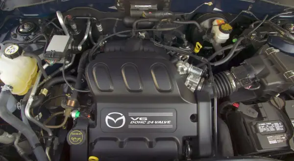 Silnik V6 DOHC 24-zaworowy w Mazda Tribute. Widoczny zbiornik płynu chłodniczego, akumulator i elementy układu dolotowego.