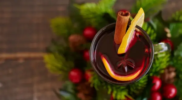 Glogg przepis: aromatyczny grzaniec z pomarańczą, cytryną i cynamonem, otoczony świątecznymi gałązkami.