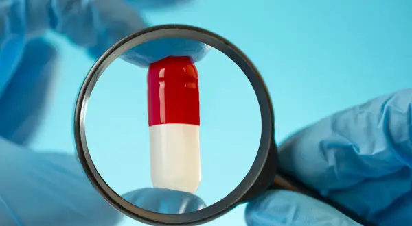 Rękawiczki badają kapsułkę z lupą. Czy to tramadol bez recepty?