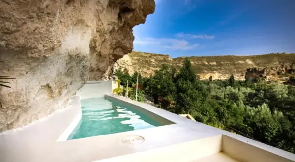 Piscina privada en cueva, ideal para una escapada fin de semana cerca de Madrid. Disfruta del paisaje verde y el cielo azul.