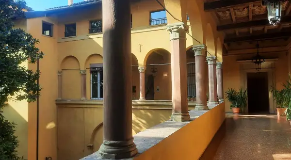 Portico con colonne e archi, tipico della casa di Lucio dalla a Bologna. Luce solare illumina il pavimento lucido.