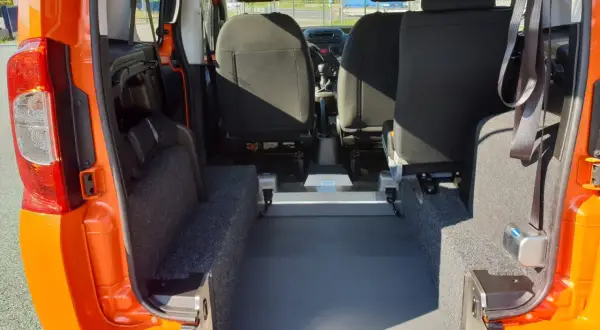 Interno di un Fiat Qubo arancione, con sedili posteriori e ampio spazio per il bagagliaio. Le dimensioni del bagagliaio sono ideali per trasporti.