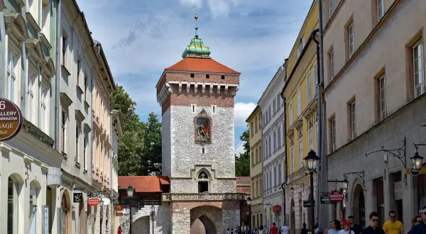 Brama Floriańska w Krakowie, majestatyczna wieża z czerwoną dachówką i kamienną fasadą, wita spacerowiczów.