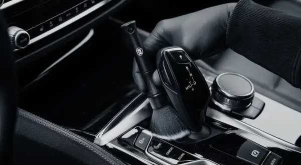 Rękawiczka czyści szczoteczką błyszczące piano black wokół dźwigni biegów.
