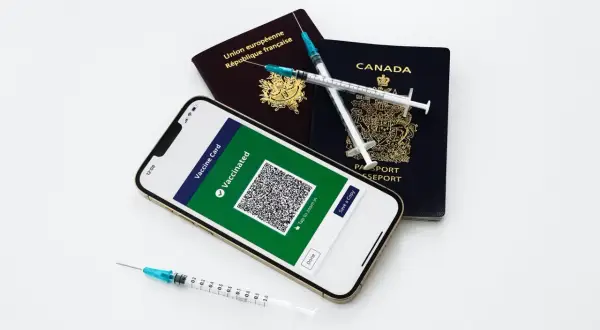 Gotowi na podróż? Paszporty, telefon z potwierdzeniem szczepień i strzykawki symbolizują przygotowania do wyjazdu.
