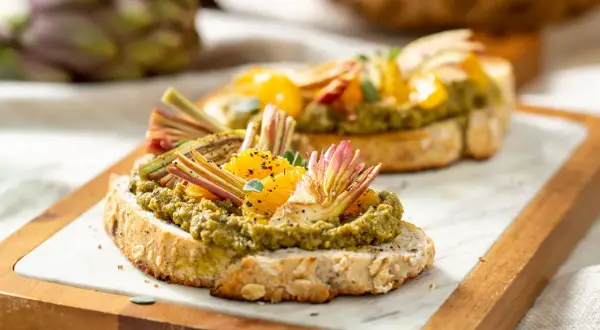 Deliziosi crostini con paté di carciofi, spicchi d'arancia e finocchietti croccanti su pane integrale tostato.