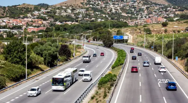 Voiture sur autoroute en Espagne, respectant la limitation vitesse espagne. Paysage vallonné avec des maisons en arrière-plan.