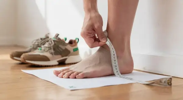 Misurare il piede per capire la calzata perfetta. Scarpe in attesa.