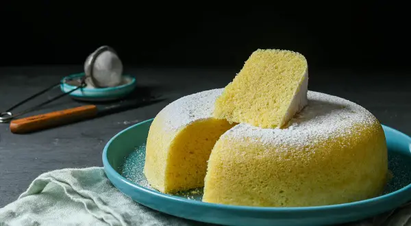 Delicioso bizcocho esponjoso, ideal para un mug cake yogur, espolvoreado con azúcar glas sobre un plato turquesa.