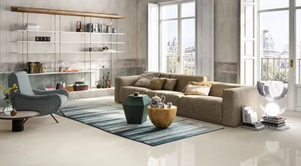 Salotto moderno con divano chevron, poltrona a zig-zag e scaffali bianchi. Pavimento in gres porcellanato color avorio.