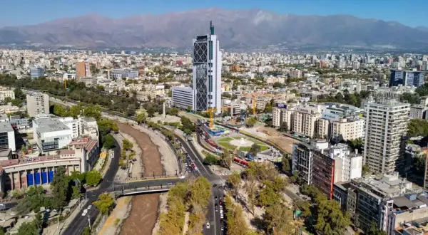 Widok na nowoczesną architekturę i rzekę w Santiago, stolicy Chile, z górami w tle.
