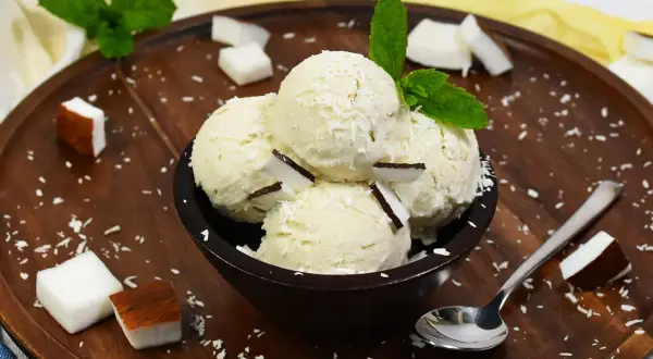 Schüssel mit Kokosnuss-Eis, garniert mit Kokosraspeln und Minze. Perfekt, um Kokosnuss Eis selber machen zu wollen!
