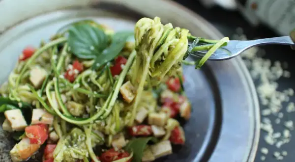 Délicieuses pâtes aux légumes sautés, un plat coloré et sain avec des courgettes en spirales, des tomates cerises et du basilic frais.