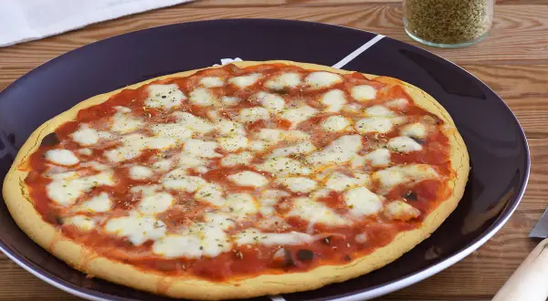 Pizza de garbanzos con queso derretido y salsa de tomate, lista para disfrutar.