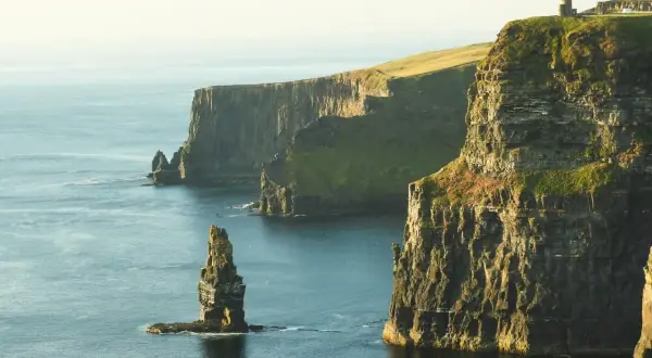Klify Moheru – obowiązkowy punkt na mapie "Irlandia co zobaczyć". Majestatyczne skały wpadające do oceanu, z wieżą widoczną na szczycie.