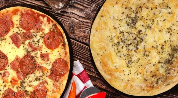 Dos pizzas recién horneadas, una de pepperoni y otra de queso, listas para disfrutar en la pizzeria Carboneras.