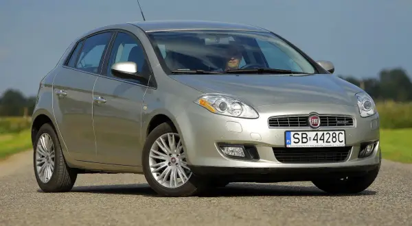 Srebrny Fiat Bravo 2 z wyraźnymi żarówkami reflektorów, zaparkowany na drodze.