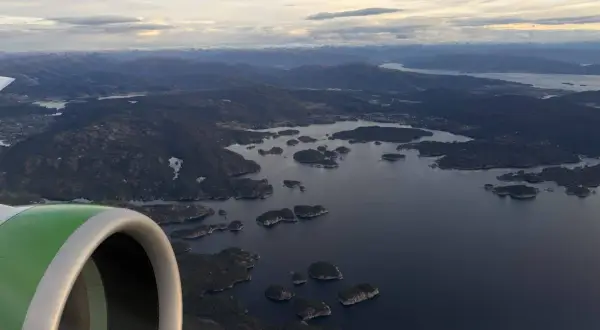 Flugzeugfenster mit Blick auf norwegische Schärenlandschaft. Gute Widerøe Airline Erfahrungen auf dieser Route.