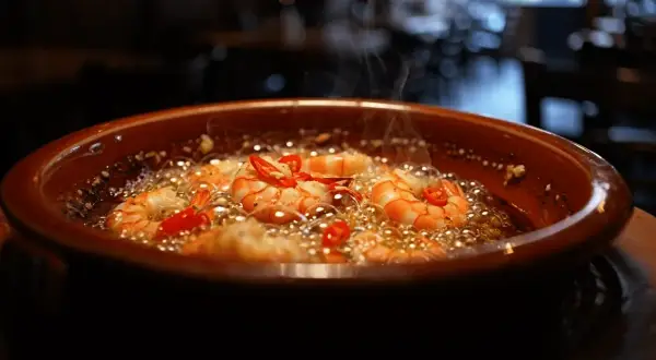 Gambas al ajillo receta: jugosas gambas cocinándose en aceite burbujeante con ajo y guindilla.