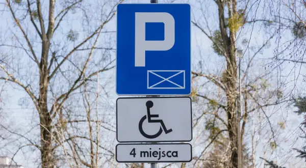Znak P z kopertą i symbolem wózka inwalidzkiego, informujący o 4 miejscach parkingowych dla niepełnosprawnych.