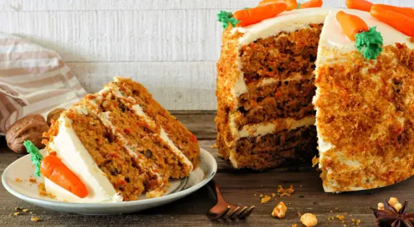 Delicioso carrot cake receta original inglesa, con capas de bizcocho y crema, decorado con zanahorias de mazapán.