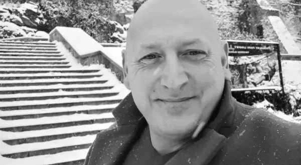 Jacek Wójcik, w zimowej scenerii, na tle zaśnieżonych schodów. Wiek nie jest widoczny, ale uśmiech sugeruje radość.