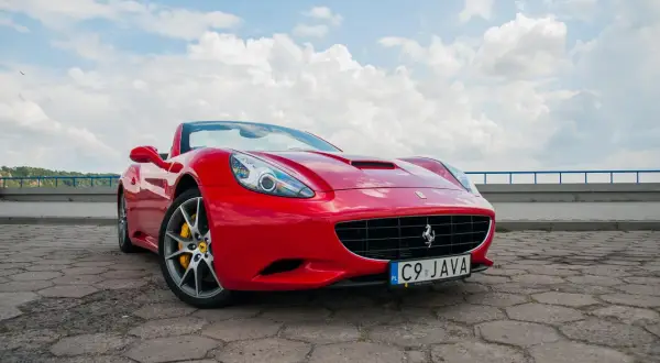 Czerwone Ferrari California z żółtymi zaciskami hamulcowymi na tle błękitnego nieba z chmurami.