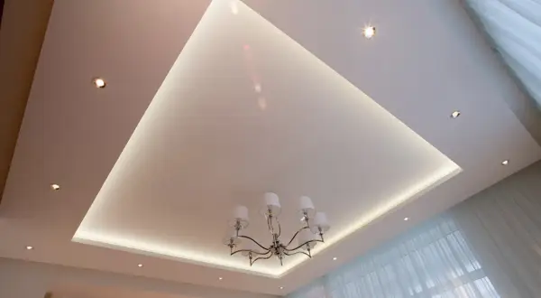 Nowoczesne aranżacje sufitów podwieszanych z subtelnym podświetleniem LED i eleganckim żyrandolem. Wzory tworzą przestrzeń.