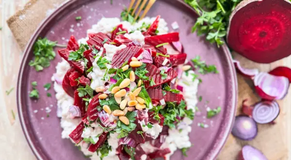 Rote Bete Salat nach Omas Art: ein cremiger Salat mit Rote Bete, Zwiebeln, Pinienkernen und frischer Petersilie, serviert auf einem lila Teller.