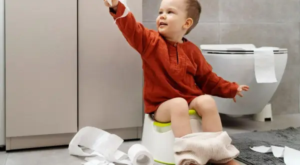 Bambino di 4 anni sul vasino, con rotoli di carta igienica sparsi. Un piccolo disastro, ma un grande passo verso l'indipendenza!
