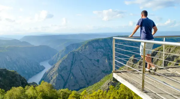 Hombre en el mirador de Cabezoas, contemplando un cañón con un río serpenteante y montañas cubiertas de vegetación.