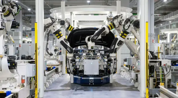 Roboterarme montieren ein Autoteil in einer Fabrik. Bosch KI steuert die präzisen Bewegungen.