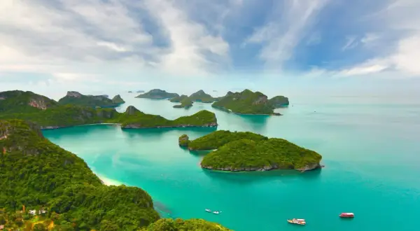 Grüne Inseln im türkisfarbenen Meer, ein Paradies für die beste Reisezeit Asien. Boote gleiten auf dem Wasser.
