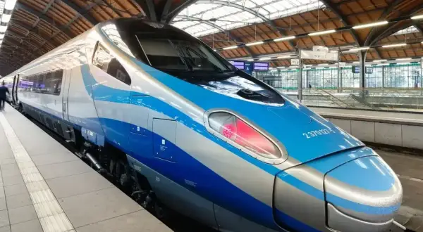 Nowoczesny pociąg Pendolino EIC z niebiesko-srebrnym malowaniem stoi na peronie.