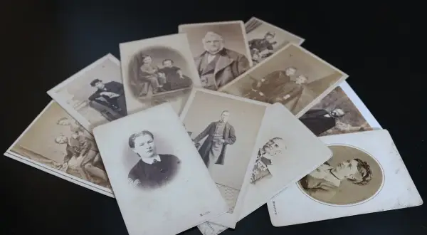 Un tas de vieilles photographies, peut-être de la commune de naissance, montrant des hommes, des femmes et des enfants en tenues d'époque.