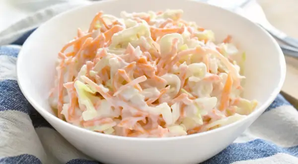 En skål med krämig coleslaw, perfekt som tillbehör till grillat. Den här godaste coleslawen är en klassiker som passar till det mesta.