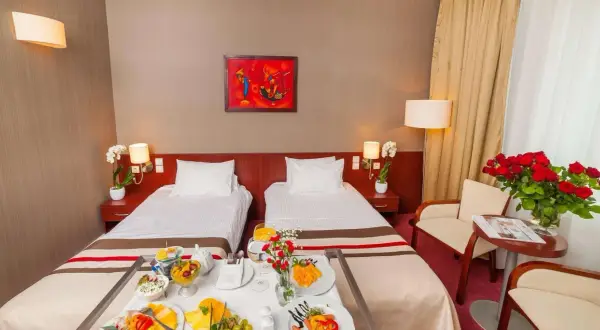 Pokój hotelowy z dwoma łóżkami, śniadaniem na tacy i bukietem róż. Idealne miejsce na pobyt, zgodnie z premier kraków hotel opinie.