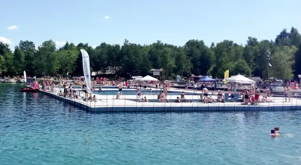 Słoneczny dzień nad wodą w Balatonie Trzebinia. Ludzie odpoczywają na pomoście i kąpią się w jeziorze.