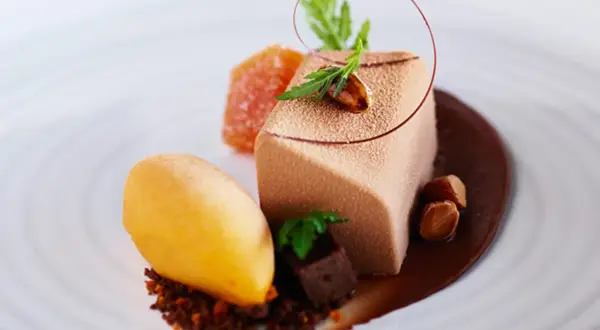 En elegant choklad havtorn dessert med en mousse, sorbet, kanderade nötter och en chokladsås.