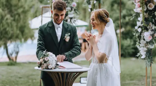 Para młoda podczas ceremonii ślubnej na tle dekoracji z kwiatów.