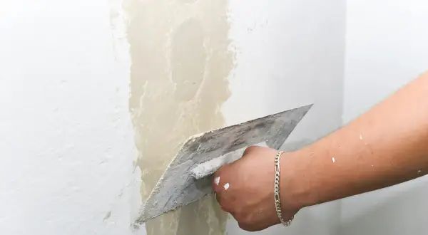 Hand mit Glättekelle bessert Rauputz aus.