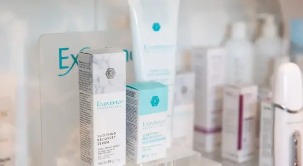 Produkty Exuviance na półce: serum łagodzące i peeling/booster.