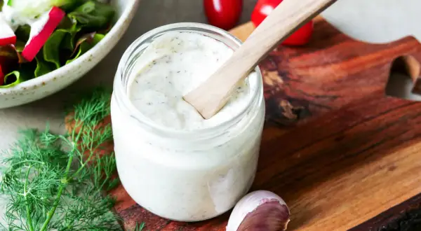 Ein Glas cremiges Sylter Dressing mit Dill und Knoblauch, bereit für einen frischen Salat.