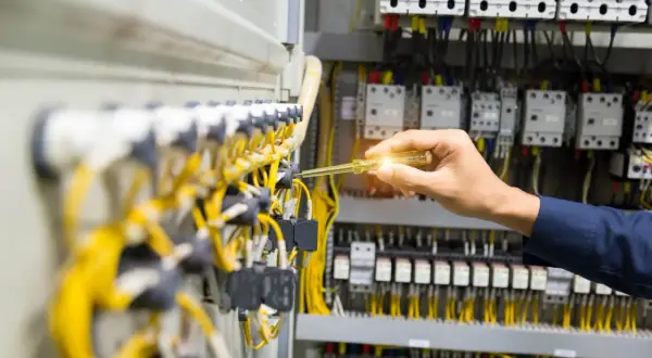 Elektryk sprawdza instalację elektryczną. Dokumentacja ZUS wykaz stanowisk pracy w szczególnych warunkach może być potrzebna przy pracach z takim okablowaniem.