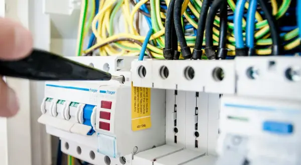 En elektriker justerar en säkring i elcentralen, en viktig del för att hålla nere driftskostnader villa.